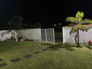 a backyard at night with a white fence and a palm tree at Chalé 3 vista para montanha in Itatiaia