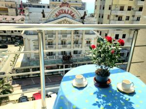 a table with a flower on a balcony with a building at Appartament ZEA in Durrës +6 photos