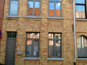 a brick building with a door and windows at Guesthouse Oude Houtmarkt in Ieper