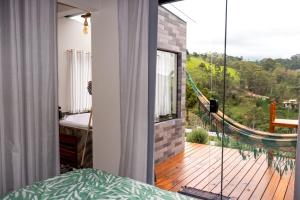 a room with a balcony with a large glass window at chalé com Hidro e Vista panorâmica para Serra in Paraisópolis