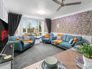 a living room with blue couches and a brick wall at Churchill Apartment- 4 Beds- Free Parking- Near NEC BHX & HS2 in Coleshill