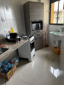 a kitchen with a stove and a microwave at Loft reserva do Sahy- condado in Mangaratiba