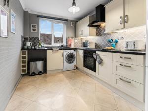 a kitchen with white cabinets and a washer and dryer at Churchill Apartment- 4 Beds- Free Parking- Near NEC BHX & HS2 in Coleshill