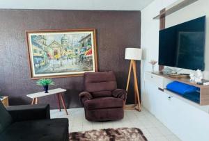 a living room with a chair and a television at Casa com 3 quartos carnaval Olinda in Olinda