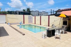 a swimming pool with a table and an umbrella at Casa com 3 quartos carnaval Olinda in Olinda