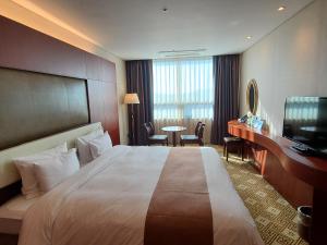 a hotel room with a large bed and a desk at Sun Valley Hotel in Yeoju