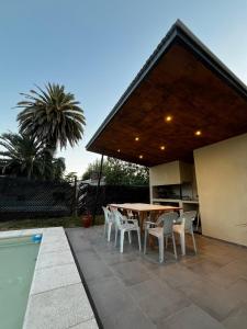 a patio with a table and chairs next to a pool at Casa con pileta Funes in Funes