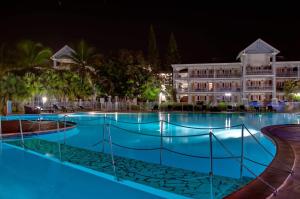 a swimming pool in front of a hotel at night at Appartement à la Résidence LA PLANTATION RESORT and SPA in Saint-François