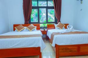 two beds in a room with a window at Mountain View Hostel in Bố Trạch