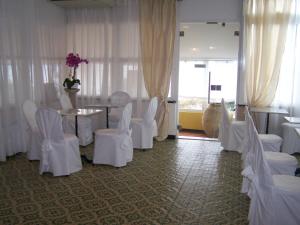 a dining room with white chairs and a table and a room with a table at Hotel La Giara in Recco