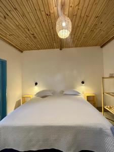 a bedroom with a white bed with a wooden ceiling at Pousada Buji in Maracajaú