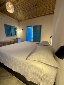 a bedroom with a white bed with a blue door at Pousada Buji in Maracajaú