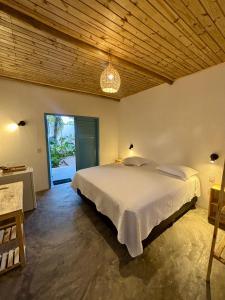 a bedroom with a large bed and a large window at Pousada Buji in Maracajaú