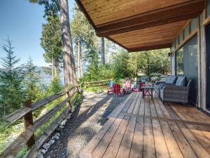 a wooden deck with chairs and tables on a house at Oceanfront view 2 entertainment areas -Pet Friendly in Port Renfrew