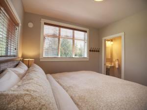 a bedroom with a large bed and two windows at Oceanfront & Amazing Views - Pet Friendly - 2bdrm in Port Renfrew