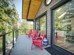 a deck with red chairs and a clock on a house at Oceanfront & Amazing Views - Pet Friendly - 2bdrm in Port Renfrew