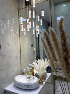 a bathroom with a sink and a mirror and chandelier at The Grand CentraL Studio & Люкс Студия в Центре Города Алматы in Almaty