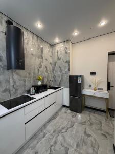 a kitchen with white cabinets and a black refrigerator at The Grand CentraL Studio & Люкс Студия в Центре Города Алматы in Almaty