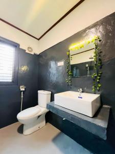 a bathroom with a white toilet and a sink at Windy Oasis in Hikkaduwa