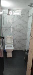 a bathroom with a white toilet and a marble wall at Ivory Suites Meadows in Kozhikode