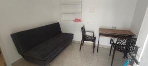 a black couch in a room with a desk and chairs at Ivory Suites Meadows in Kozhikode