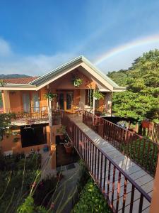 a house with a balcony with a rainbow in the background at Mi Casa Su Casa Monteverde in Monteverde Costa Rica
