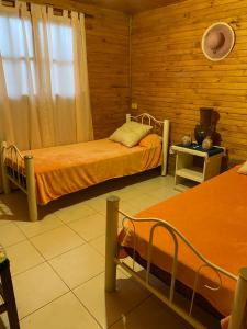 two beds in a room with wooden walls at Cabañas Los Lapachos in Chicoana