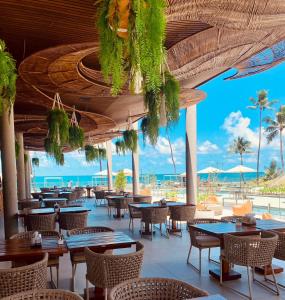 a restaurant with tables and chairs and a view of the ocean at Resort beira mar in Porto De Galinhas