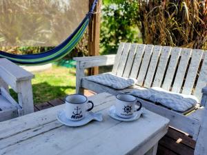 two cups and saucers sitting on a wooden table at Luz Marina Cabaña Pettit Hidromasaje in Punta Colorada