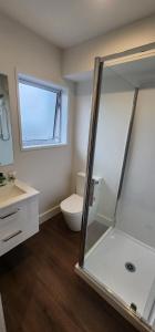 a bathroom with a toilet and a glass shower at Waikato Hospital Motel in Hamilton +7 photos