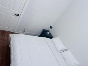 a white bed in a room with a white wall at Cozy single room in Fall River