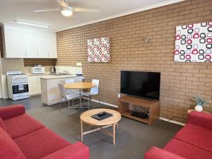 a living room with a red couch and a kitchen at Parkview Motor Inn and Apartments in Wangaratta