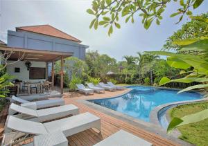 a swimming pool with white lounge chairs next to a house at Harmony Beach Suite in Seminyak