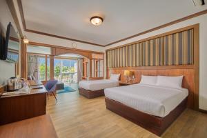 a bedroom with two beds and a desk and a television at Le Erawan Phang Nga Hotel in Phangnga