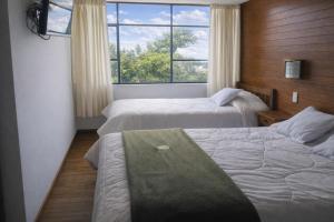 a hotel room with two beds and a window at Hostal Arias in Oxapampa