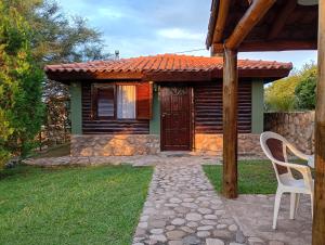 a cabin with a table and a chair in front of it at Cabaña de troncos en Nono, Córdoba in Nono