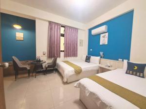 a hotel room with two beds and a table and chairs at 小蘋果民宿 in Jinning