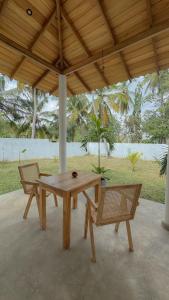 a wooden picnic table and two chairs under a pavilion at Villa Palm in Rekawa