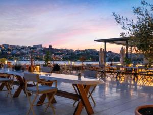 a rooftop patio with tables and chairs at dusk at Rixos Tersane Istanbul in Istanbul