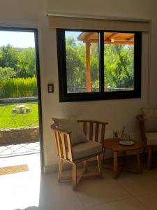 a room with a chair and a table and a window at Anicca Posada in San Marcos Sierras