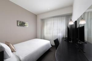 a hotel room with a white bed and a window at Palace Hotel Omiya in Saitama
