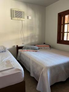 a bedroom with two beds and a air conditioner on the wall at Residencial Casa Laranja - Casas na Praia da Ferrugem in Garopaba
