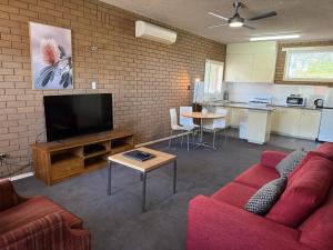a living room with a red couch and a flat screen tv at Parkview Motor Inn and Apartments in Wangaratta