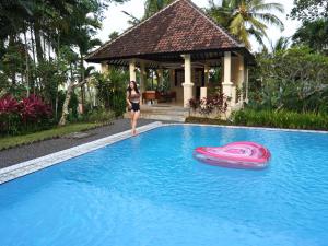 a woman standing in a swimming pool with a frisbee at Domisili Ijen Cliff By Fays Hospitality in Banyuwangi