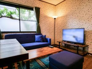 a living room with a blue couch and a tv at Villa228KASAMA in Kasama