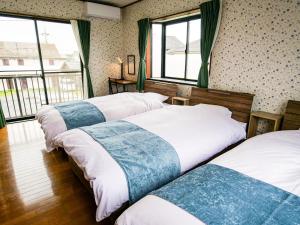 two beds in a room with windows at Villa228KASAMA in Kasama