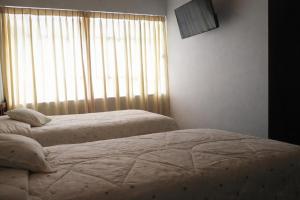 two twin beds in a bedroom with a window at Hostal Arias in Oxapampa