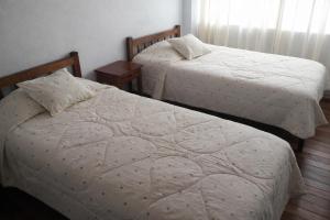two twin beds in a room with at Hostal Arias in Oxapampa