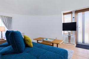 ein blaues Sofa in einem Wohnzimmer mit einem Fernseher in der Unterkunft Uruma Dome Okinawa in Uruma