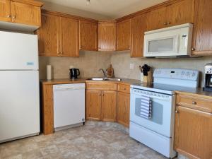 a kitchen with white appliances and wooden cabinets at Quaint Lonsdale Suite in Red Deer